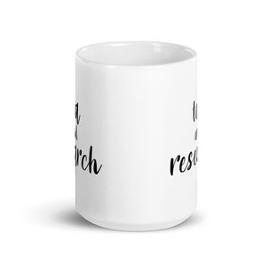 May include: White ceramic mug with black text that reads "tea and research" on one side and "tea and research" on the other side.