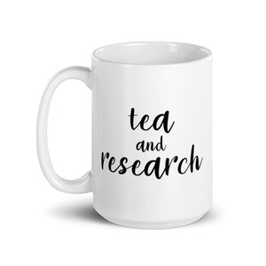 May include: White ceramic mug with a black inscription that reads "tea and research".