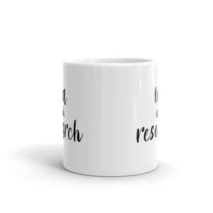 May include: White ceramic mug with black text that reads "tea and research".