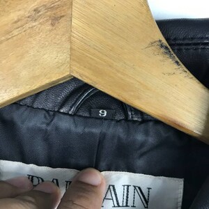 May include: Black leather jacket with a Balmain label and a size 9 tag. The jacket has a zipper closure and a stand-up collar.
