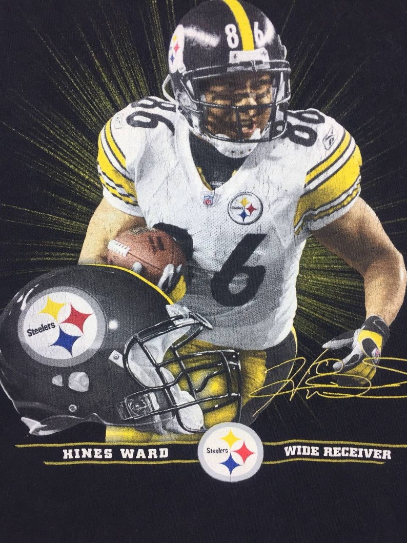 K&ouml;nnte beinhalten: Schwarzes T-Shirt mit einem Grafikdruck von Hines Ward, einem Wide Receiver der Pittsburgh Steelers, der ein Football-Trikot tr&auml;gt und einen Football h&auml;lt. Die Grafik enth&auml;lt das Steelers-Logo und die Unterschrift von Hines Ward. Der Text "Hines Ward" und "Wide Receiver" ist unterhalb der Grafik aufgedruckt.