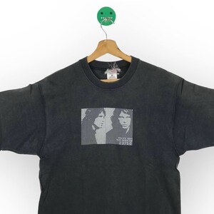 Puede incluir: Camiseta negra con un estampado descolorido de dos caras de hombres y el texto "Police Dept. New York City 23750".