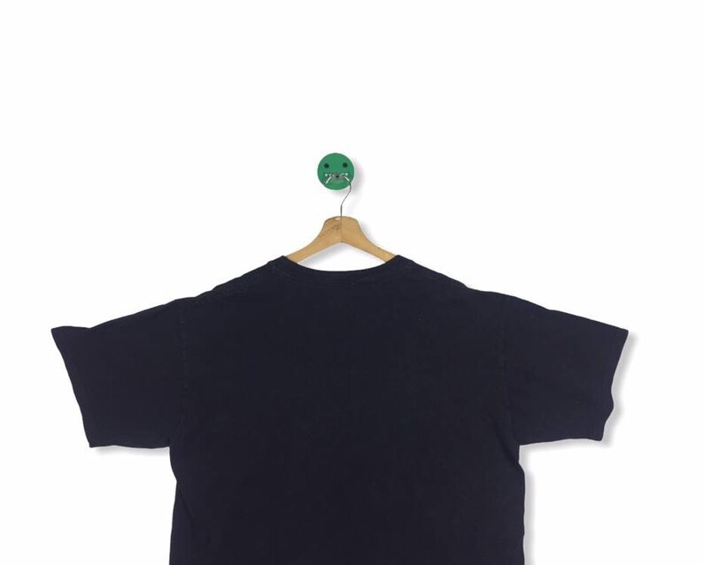 K&ouml;nnte beinhalten: Ein schwarzes T-Shirt mit kurzen &Auml;rmeln, das an einem Holzb&uuml;gel h&auml;ngt. Das T-Shirt ist einfarbig und hat keine sichtbaren Grafiken oder Texte.