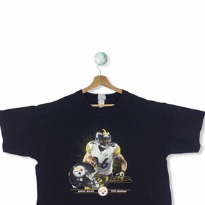 K&ouml;nnte beinhalten: Schwarzes T-Shirt mit einem Grafikdruck von Hines Ward, einem Wide Receiver der Pittsburgh Steelers, der eine schwarz-gelbe Uniform tr&auml;gt und einen Football h&auml;lt. Der Text "Hines Ward" und "Wide Receiver" ist unter dem Grafikdruck aufgedruckt.