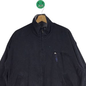 May include: A dark blue zip-up jacket with a stand-up collar and a zippered pocket on the left side.