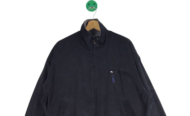 May include: A dark blue zip-up jacket with a stand-up collar and a zippered pocket on the left side.