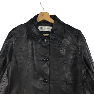 May include: Black leather jacket with a button closure and a label that reads "BALMAIN PARIS".