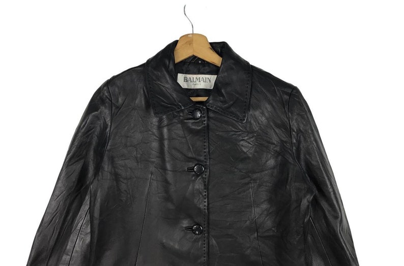 May include: Black leather jacket with a button closure and a label that reads "BALMAIN PARIS".