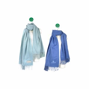 Puede incluir: Dos bufandas colgadas en perchas. La bufanda de la izquierda es azul claro y la bufanda de la derecha es azul. La bufanda azul tiene la palabra "LANVIN" bordada.