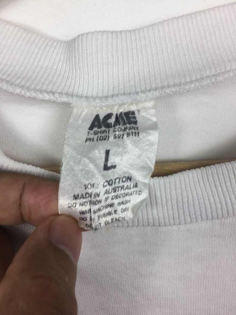 May include: White cotton t-shirt tag with the text "ACME T-SHIRT COMPANY PH (02) 591 5111" and "101% COTTON MADE IN AUSTRALIA DO NOT IRON IF DECORATED WASH MACHINE WARM DO NOT TUMBLE DRY DO NOT BLEACH".