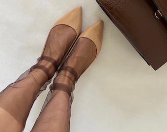 Puede incluir: Un par de zapatos de salón de charol nude con calcetines transparentes marrones. Un bolso de mano marrón de piel de cocodrilo con una correa de cadena dorada está en el fondo.