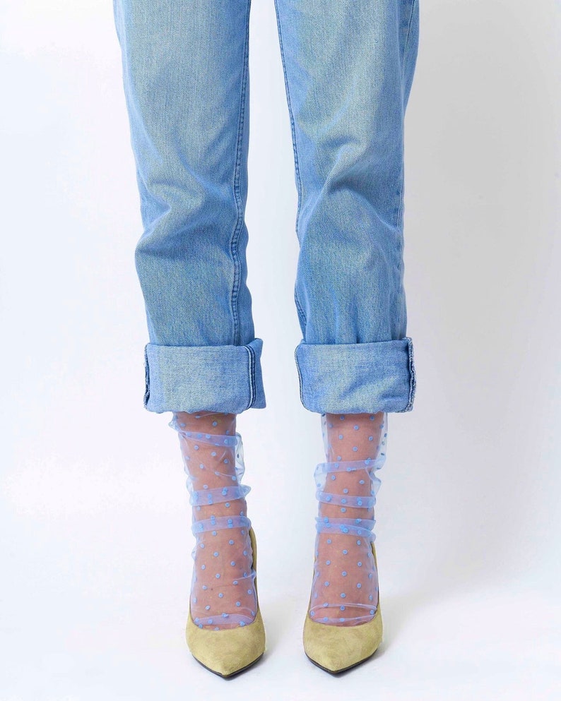 May include: A pair of light blue polka dot sheer socks with rolled up blue jeans and light brown high heels.
