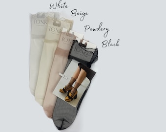 May include: Four pairs of sheer socks with lace trim in white, beige, powdery, and black. The socks are displayed on a white background with the color names written above each pair.