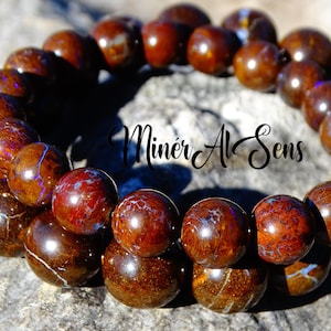May include: A double-strand bracelet made of brown and iridescent opal beads. The beads are round and have a smooth, polished finish. The bracelet is approximately 20 cm in length.