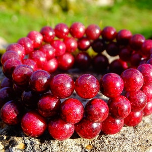 May include: A red gemstone bracelet with multiple strands of round beads. The beads are a deep red color and have a glossy finish.