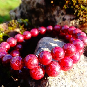 May include: A red gemstone bracelet with round beads. The bracelet is made of natural stones and is a beautiful piece of jewelry.