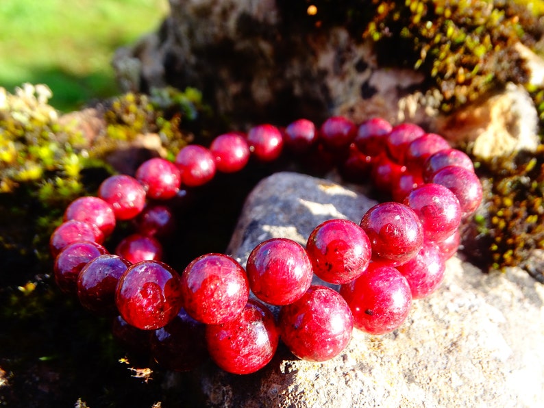 May include: A red gemstone bracelet with round beads. The bracelet is made of natural stones and is a beautiful piece of jewelry.