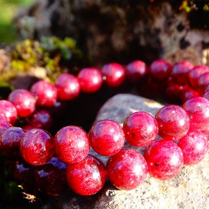 May include: A double-strand bracelet made of red gemstone beads. The beads are round and have a smooth, polished finish.