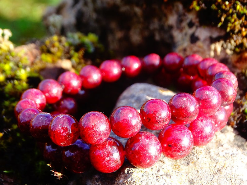 May include: A double-strand bracelet made of red gemstone beads. The beads are round and have a smooth, polished finish.