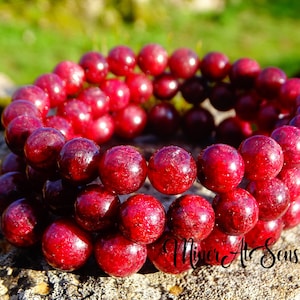 Peut inclure: Un bracelet en pierres précieuses rouges avec des perles rondes. Le bracelet est composé de plusieurs rangs de perles superposés.
