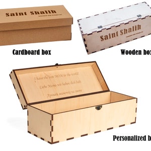 May include: Three boxes are shown: a brown cardboard box, a light-colored wooden box, and a personalized wooden box. The cardboard box and wooden box have the text "Saint Shalih" on them. The personalized box has text inside.