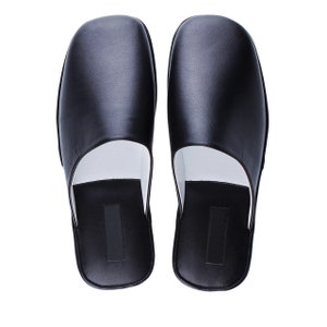 May include: A pair of black leather slippers with a white lining. The slippers have a simple, classic design.