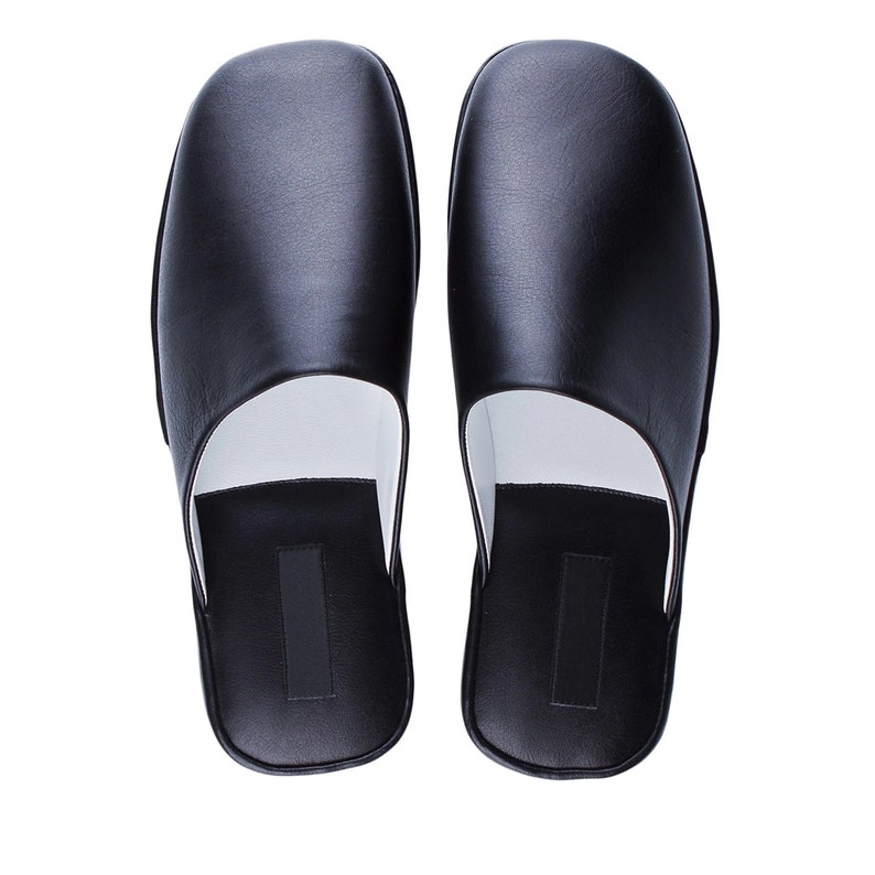 May include: A pair of black leather slippers with a white lining. The slippers have a simple, classic design.