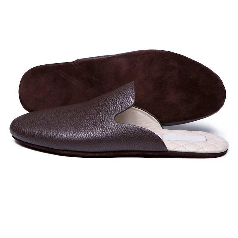May include: Brown leather slippers with a suede insole and a white quilted lining.