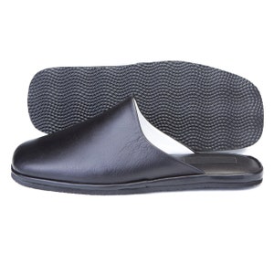 May include: Black leather slippers with a textured rubber sole. The slippers have a white lining and a closed toe.