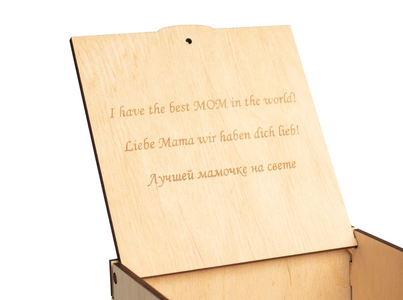 May include: Wooden box with a hinged lid. The lid is open and the inside of the box is visible. The lid has an inscription that reads "I have the best MOM in the world! Liebe Mama wir haben dich lieb! Лучшей мамочке на свете"