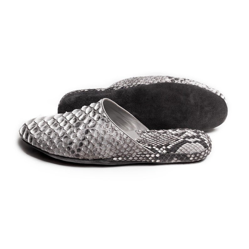 May include: A pair of gray and black snake skin slippers. The slippers have a pointed toe and a flat sole.
