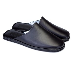 May include: A pair of black leather slippers with a closed toe and a slip-on design.