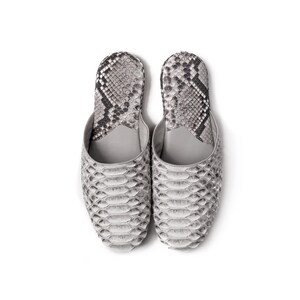 May include: A pair of gray and black snakeskin slippers. The slippers have a pointed toe and a flat sole.