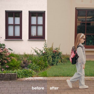 May include: A young person wearing a denim jacket and jeans walks down a sidewalk in front of a house with a pink backpack. The house has two windows with brown frames and a large window with a brown frame on the right side of the image.
