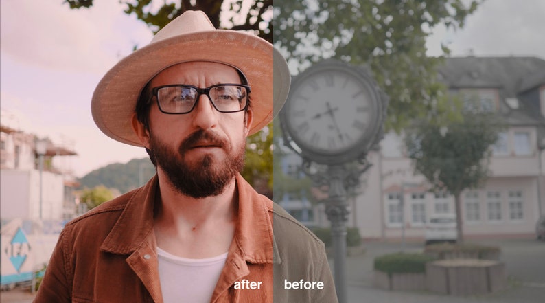 May include: A man wearing a brown jacket, a white t-shirt, a beige hat, and glasses is standing in front of a clock tower. The clock tower is in the background and is out of focus. The man is looking directly at the camera.