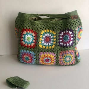 May include: A large, handmade crochet tote bag in olive green, featuring colorful floral squares. The bag has a matching small key holder. The bag has a leather tag that says "Rome".