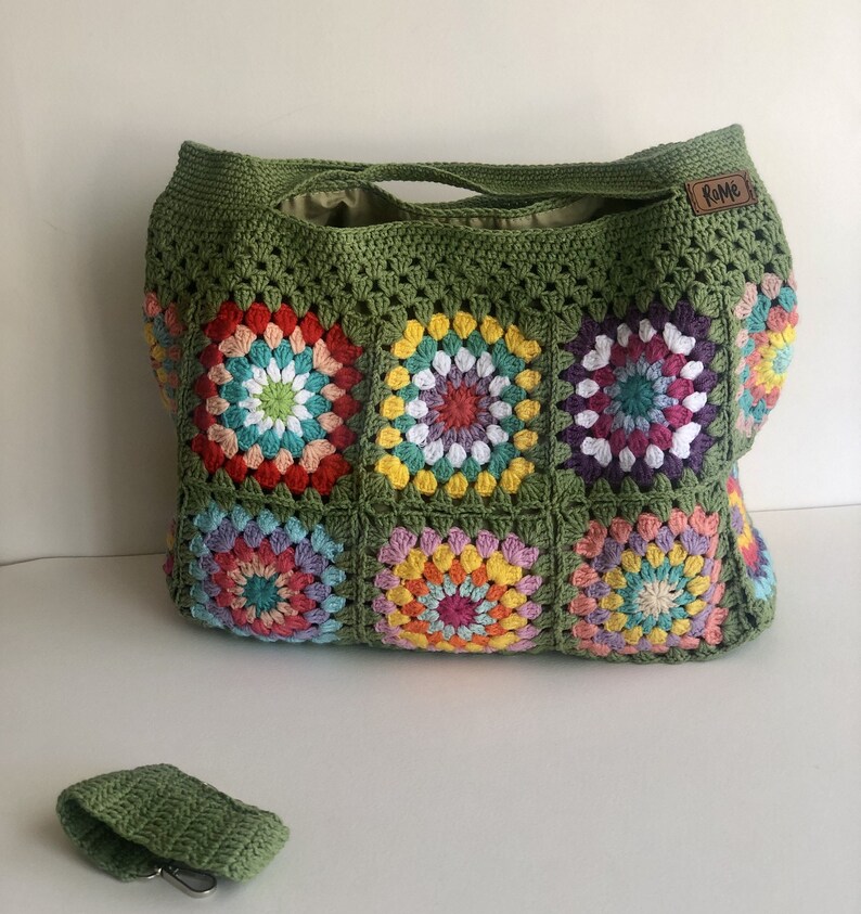 May include: A large, handmade crochet tote bag in olive green, featuring colorful floral squares. The bag has a matching small key holder. The bag has a leather tag that says "Rome".