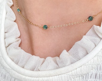 May include: A gold chain necklace with three green gemstone beads.