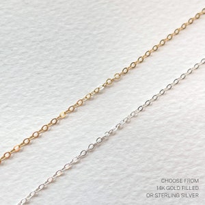 May include: Two chains, one gold filled and one sterling silver, lay side by side on a white surface. Choose from 14k gold filled or sterling silver.