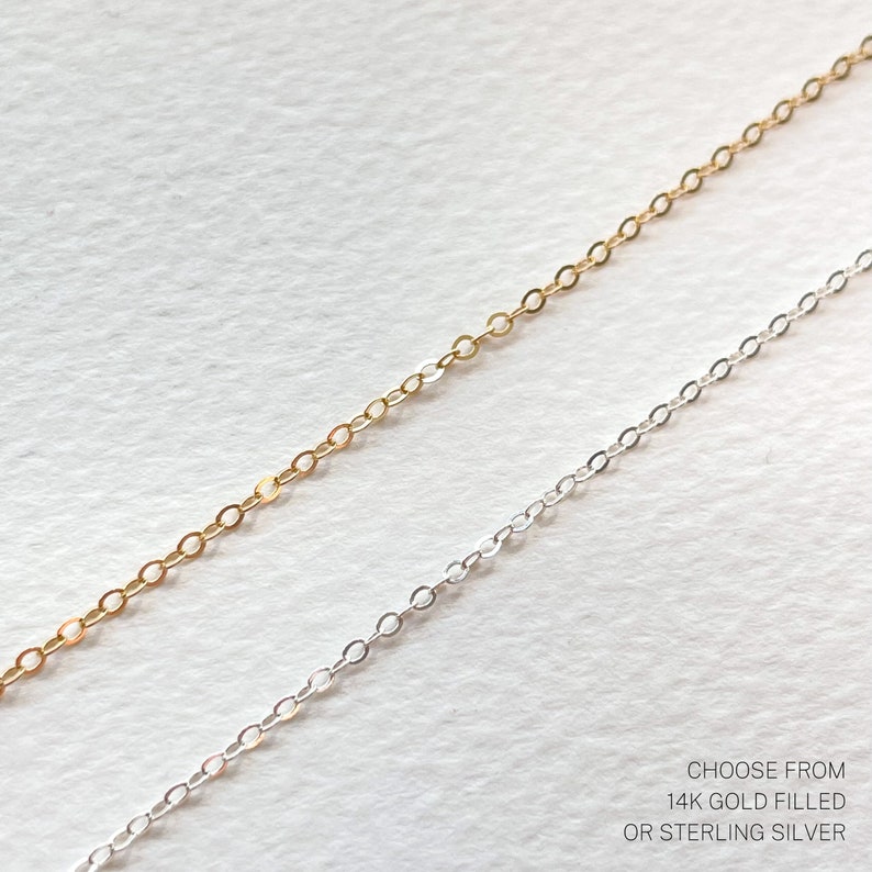 May include: Two chains, one gold filled and one sterling silver, lay side by side on a white surface. Choose from 14k gold filled or sterling silver.