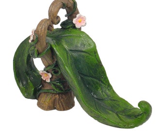 May include: A miniature fairy garden slide made of green resin with a brown wooden base and pink flowers.