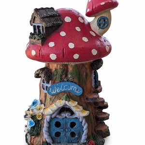 Puede incluir: Una caprichosa casa con forma de hongo con un sombrero rojo salpicado de puntos blancos. La casa tiene una puerta azul, una pequeña ventana y un letrero que dice "welcome". La estructura está diseñada para parecerse a un tronco de árbol, con una pequeña escalera.