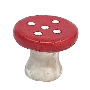 Puede incluir: Figura decorativa de hongo con sombrero rojo y puntos blancos. El tallo es de color gris claro. Esta pieza caprichosa es una adición encantadora a cualquier decoración del hogar, perfecta para un jardín de hadas o una exhibición en estanterías.