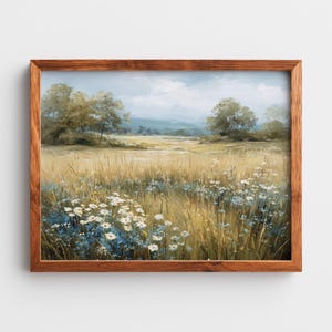 May include: A framed landscape painting depicts a field of tall, golden grass and wildflowers under a cloudy sky. White and blue flowers dot the foreground. The painting is in a wooden frame.