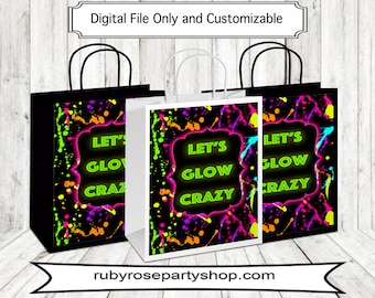 May include: Three white paper gift bags with black handles. The bags have a black background with neon green, pink, yellow, and blue paint splatters. The text "Let's Glow Crazy" is written in neon green on each bag.