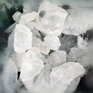 May include: A close-up of a pile of clear, white, crystalline rock salt. The salt crystals are various sizes and shapes.