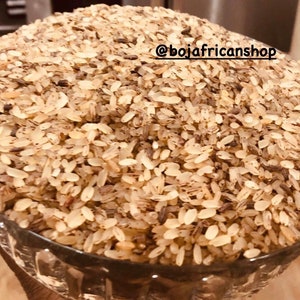 May include: A close-up shot of a clear glass bowl filled with a pile of uncooked rice. The rice grains are a mix of light tan and brown colors. The text "@bojafricanshop" is visible on the image.