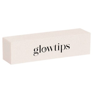 May include: An off-white rectangular block with the word "glowtips" printed in black. The block has a textured surface. The product is set against a white background. It appears to be a beauty or skincare item.