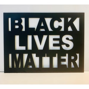 May include: Black Lives Matter sign with white letters cut out of a black background.