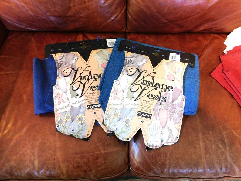May include: Two packages of blue fabric for making vintage vests. Each package includes a pattern and instructions. The packages are labeled "Vintage Vests" and feature a whimsical design with a gingerbread man, a cactus, and a sunflower.